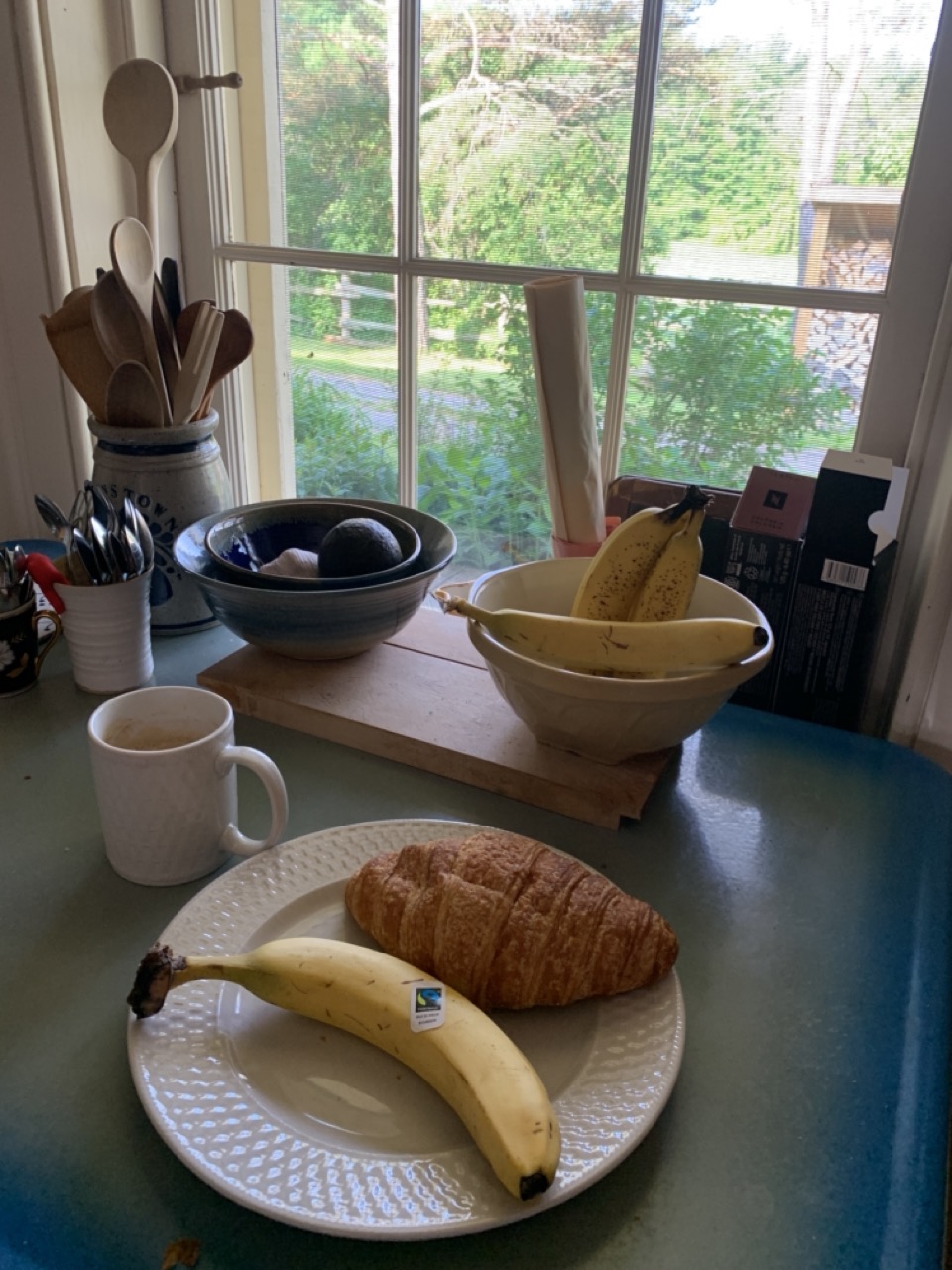 Breakfast plate with a banana, croissant, and a cup of coffee